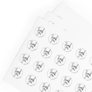 May include: A sheet of white paper with multiple black and white stickers that say "Thank you - Shop Small".