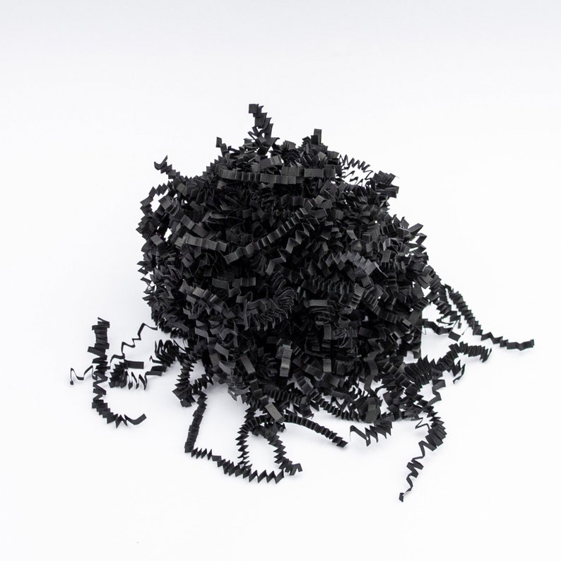 May include: A pile of black crinkle paper, a decorative filler for gift boxes and packaging. The shredded paper has a textured, wavy appearance and is arranged against a white background.