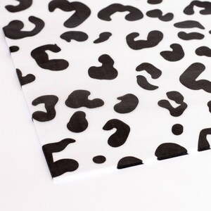 May include: Black and white leopard print wrapping paper. The paper has a white background with black leopard spots.