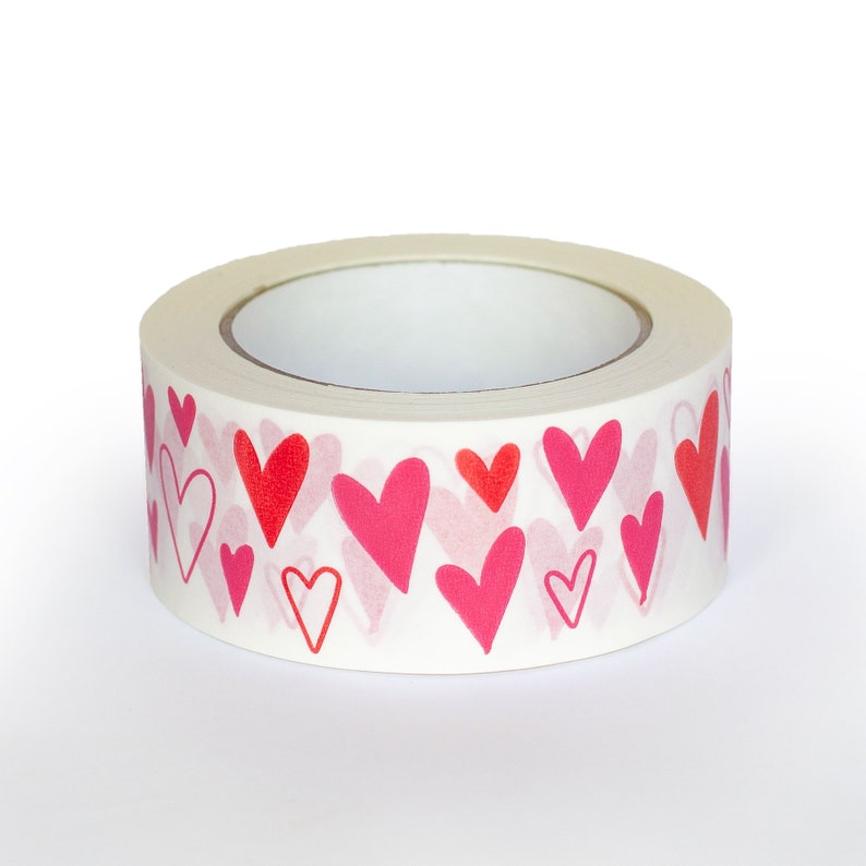 Puede incluir: Un rollo de cinta adhesiva decorativa con un patr&oacute;n repetido de corazones rojos y rosas sobre un fondo blanco. Los corazones var&iacute;an en tama&ntilde;o y estilo, algunos delineados y otros s&oacute;lidos.