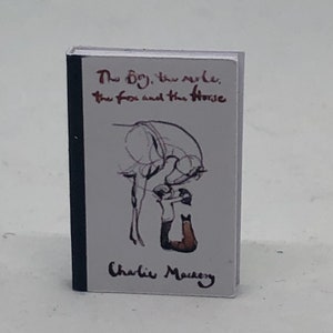 Puede incluir: Un libro blanco con una encuadernaci&oacute;n negra. La portada presenta una ilustraci&oacute;n en blanco y negro de un ni&ntilde;o acariciando un caballo. El t&iacute;tulo del libro es "The Boy, the Mole, the Fox and the Horse" de Charlie Mackesy.