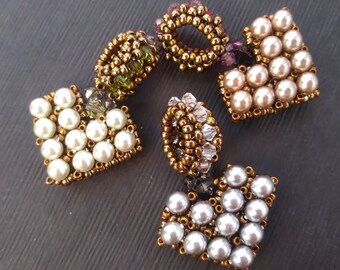 May include: A set of six beaded jewelry pieces in various shapes and colors. The pieces are made with small, round beads in shades of white, cream, gold, and green. The beads are arranged in geometric patterns, creating a unique and eye-catching design.