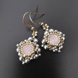 May include: A pair of silver and gold earrings with a clear crystal in the center of each earring.