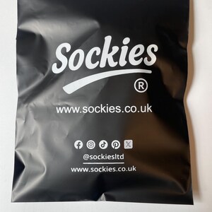 May include: Black package with the word "Sockies" in white script. Below the name is the website address www.sockies.co.uk. Social media icons and the handle @sockiesltd are also visible.