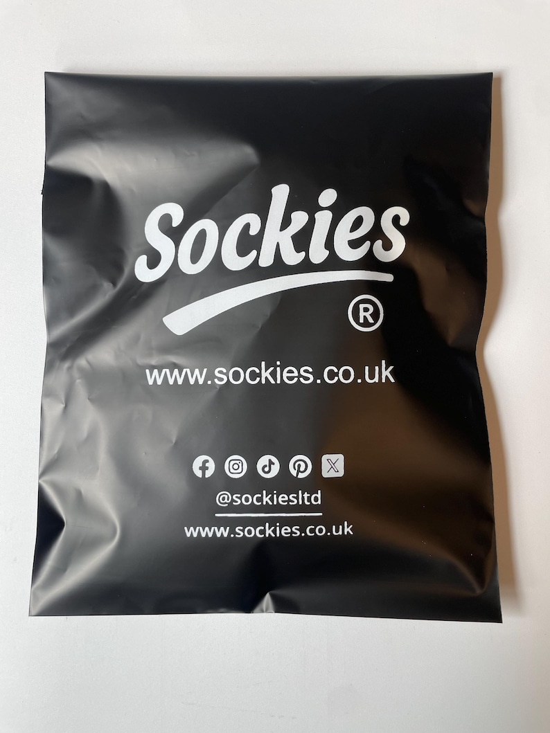 May include: Black package with the word "Sockies" in white script. Below the name is the website address www.sockies.co.uk. Social media icons and the handle @sockiesltd are also visible.