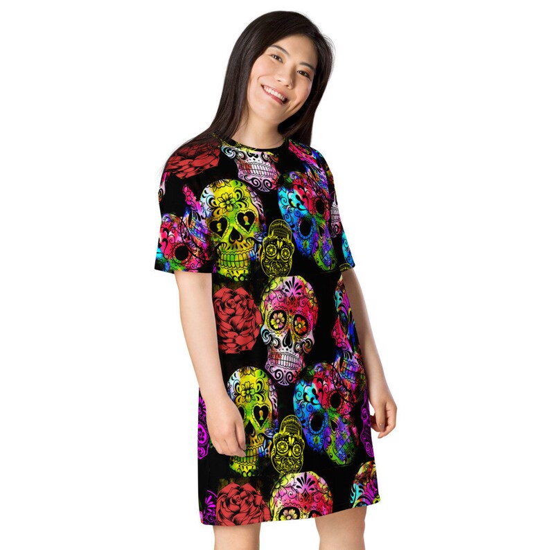 May include: A black t-shirt dress with a colorful sugar skull print. The skulls are decorated with flowers and have a bright, vibrant color scheme.