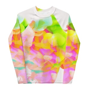 May include: A white long-sleeve shirt with a colorful abstract design featuring pink, yellow, green, and blue hues. The design is reminiscent of a watercolor painting.