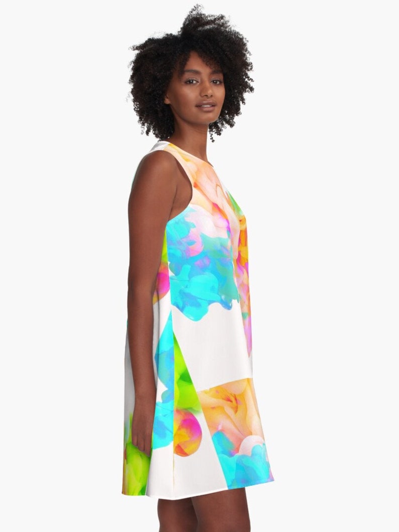 May include: A white sleeveless dress with a colorful abstract design featuring blue, green, yellow, pink, and orange. The design resembles paint splatters or ink blots.