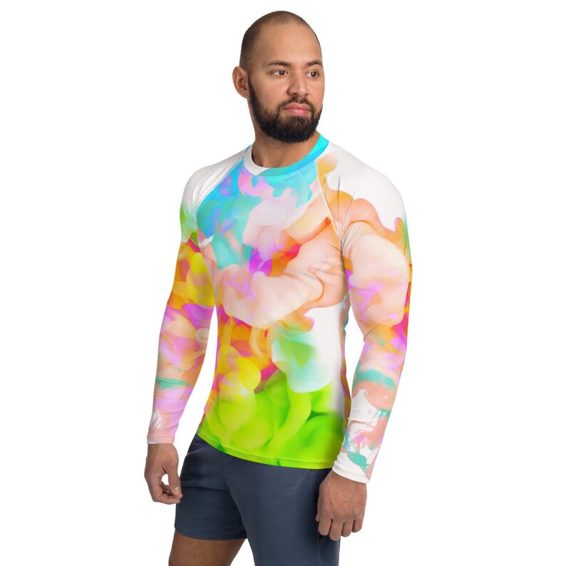 K&ouml;nnte beinhalten: Ein wei&szlig;es Langarmshirt mit einem farbenfrohen abstrakten Design. Das Design zeigt Wirbel in Rosa, Blau, Gelb und Gr&uuml;n.