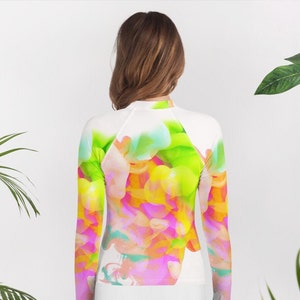 May include: White long-sleeve rash guard with a colorful abstract design featuring pink, yellow, green, and blue hues.