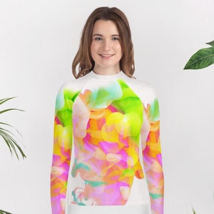 May include: White long-sleeved shirt with a colorful abstract design featuring pink, yellow, green, and blue hues.