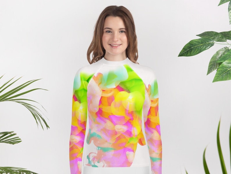 May include: White long-sleeved shirt with a colorful abstract design featuring pink, yellow, green, and blue hues.