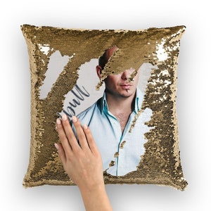 Può includere: Cuscino di paillettes dorate con un design reversibile. Un lato presenta una foto di un uomo calvo con la barba che indossa una camicia blu chiaro. L'altro lato è di paillettes dorate.