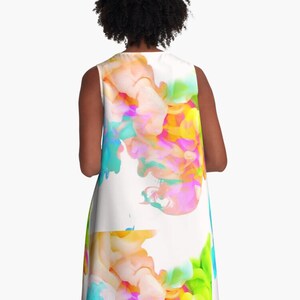 May include: A sleeveless dress with a white background and a colorful abstract design. The design features swirls of pink, blue, green, and yellow.