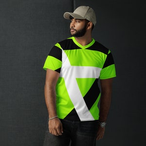Puede incluir: Una camiseta de manga corta verde, negra y blanca con un diseño geométrico. La camiseta tiene un cuello en V.