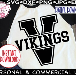 May include: A white and black baseball jersey with a large black letter V and the word "VIKINGS" in black text. The jersey is on a wooden background.