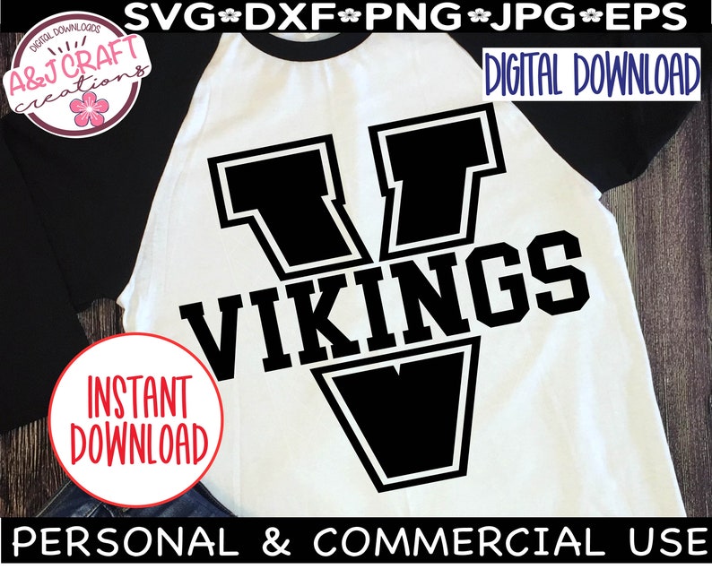 May include: A white and black baseball jersey with a large black letter V and the word "VIKINGS" in black text. The jersey is on a wooden background.
