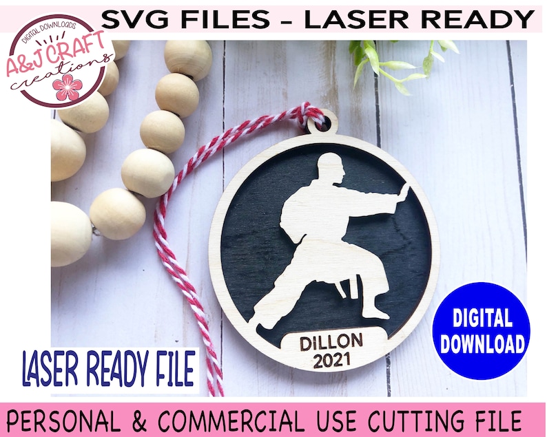 May include: A laser-cut wooden ornament featuring a silhouette of a person in a karate pose. The ornament is black with a white silhouette and the text "Dillon 2021".