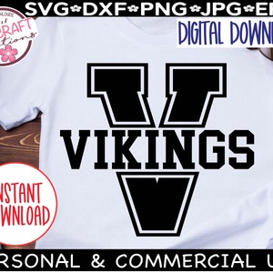 May include: A white t-shirt with a black graphic of a large letter V with the word "VIKINGS" underneath. The graphic has a thick black outline.