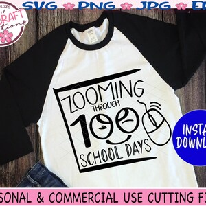May include: A white t-shirt with a black design that says "Zooming Through 100 School Days" with a cartoon mouse and two smiley faces. The design is in a black square with a white outline.