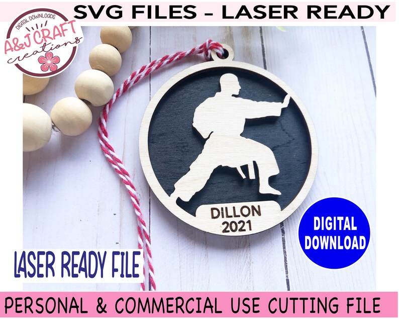 May include: A laser-cut wooden ornament featuring a silhouette of a person in a karate pose. The ornament is black with a white outline and the text "Dillon 2021" is inscribed below the figure.