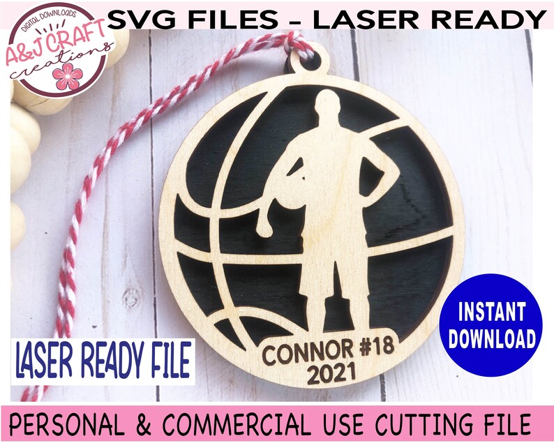 May include: A laser-ready wooden basketball ornament with a player silhouette inside a basketball design. The ornament includes the name "Connor #18 2021". The design is ready for personal and commercial use.