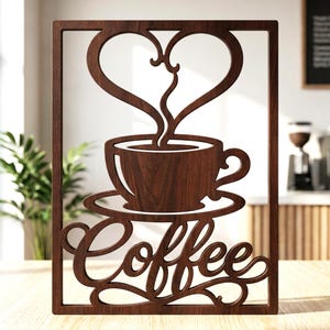 Peut inclure: Une décoration murale rectangulaire en bois brun foncé présentant une découpe représentant une tasse de café sur une soucoupe. La vapeur s'échappant de la tasse forme un cœur au-dessus. Le mot Coffee est écrit en lettres cursives en bas.