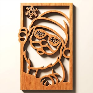 Peut inclure: Une décoration murale rectangulaire en bois présentant une découpe laser de Père Noël portant des lunettes de soleil avec le texte HO HO gravé sur les verres. Un flocon de neige est situé dans le coin supérieur gauche du cadre en bois naturel.