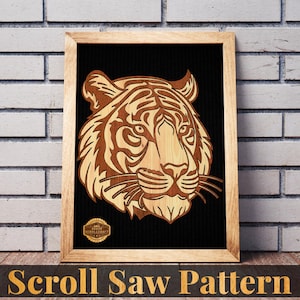 May include: A framed wooden scroll saw pattern of a tiger's head. The tiger is depicted in shades of brown and tan against a black background. The frame is light brown, and the text "Scroll Saw Pattern" is at the bottom.