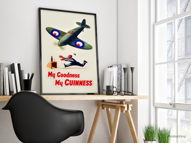 May include: A framed vintage advertisement poster featuring a green airplane with blue and red accents. The poster depicts a man reaching for a falling bottle, with the text "My Goodness My Guinness" in red.