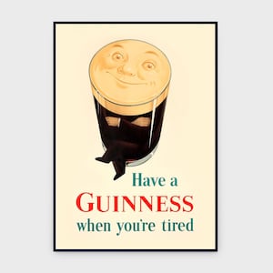 May include: A framed vintage Guinness advertisement. The image features a pint of Guinness with a smiling face, arms crossed, and legs crossed. The text reads "Have a Guinness when you're tired" in red and teal.