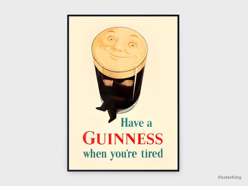 May include: A framed vintage Guinness advertisement. The image features a pint of Guinness with a smiling face, arms crossed, and legs crossed. The text reads "Have a Guinness when you're tired" in red and teal.