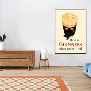 May include: A framed Guinness advertisement poster. The poster features a smiling pint of Guinness with arms and legs, with the text "Have a Guinness when you're tired" in red and green.