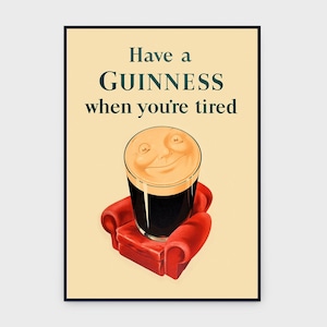 K&ouml;nnte beinhalten: Vintage Guinness-Werbeplakat. Es zeigt ein Guinness-Glas mit einem l&auml;chelnden Gesicht, das auf einem roten Sessel ruht. Der Text lautet "Have a Guinness when you're tired" in gr&uuml;nen Buchstaben auf cremefarbenem Hintergrund.