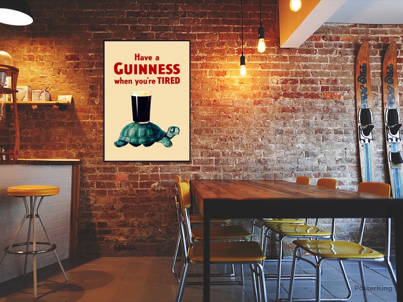 Pode incluir: Um p&ocirc;ster de estilo vintage que anuncia a cerveja Guinness. O p&ocirc;ster apresenta uma tartaruga de desenho animado carregando um copo de Guinness com o texto "Have a GUINNESS when you're TIRED".