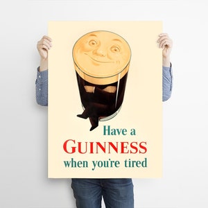 May include: Vintage Guinness advertisement poster. The poster features a smiling pint of Guinness with arms crossed, and legs crossed. The text reads "Have a Guinness when you're tired" in red and green.