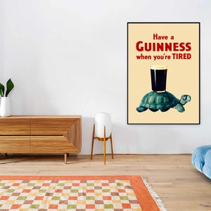 Pode incluir: Um p&ocirc;ster de estilo vintage com uma ilustra&ccedil;&atilde;o em preto e branco de uma tartaruga carregando um copo de cerveja Guinness. O p&ocirc;ster tem um fundo amarelo e o texto "Have a GUINNESS when you're TIRED" em vermelho e preto.