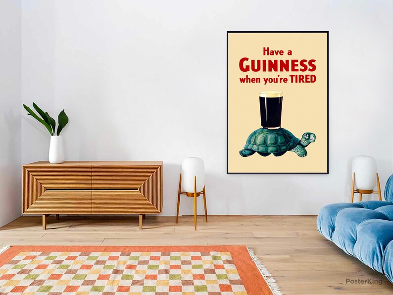 Pode incluir: Um p&ocirc;ster de estilo vintage com uma ilustra&ccedil;&atilde;o em preto e branco de uma tartaruga carregando um copo de cerveja Guinness. O p&ocirc;ster tem um fundo amarelo e o texto "Have a GUINNESS when you're TIRED" em vermelho e preto.