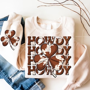 Diseño de piel de vaca Howdy PNG, sublimación de San Patricio occidental, tipografía Howdy PNG, gráfico de trébol de piel de vaca PNG, país de moda Png