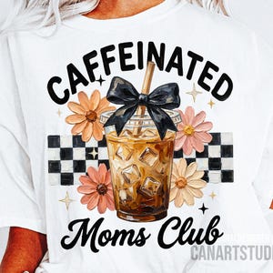 Puede incluir: Camiseta blanca con un diseño gráfico que presenta una bebida de café con cubitos de hielo, un lazo negro y las palabras "CAFFEINATED Moms Club". El diseño incluye flores y un patrón de cuadros.