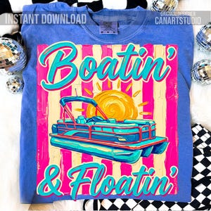May include: Blue sweatshirt with a graphic that says "Boatin' & Floatin'". The graphic features a pontoon boat, a sun, and pink and yellow stripes. The words "Instant Download" and "Original Designer CanArtStudio" are also visible.