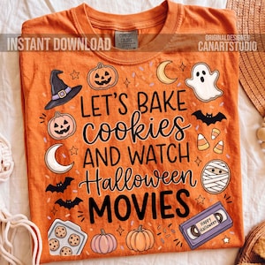 May include: Orange Comfort Colors t-shirt with a Halloween theme. The shirt features the text "LET'S BAKE cookies AND WATCH Halloween MOVIES" with illustrations of pumpkins, bats, a ghost, and a VHS tape that says "Happy Halloween".