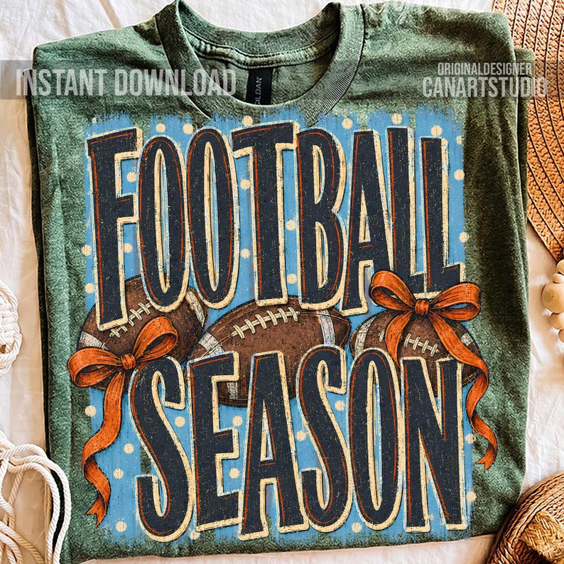 K&ouml;nnte beinhalten: Ein meliertes olivgr&uuml;nes T-Shirt mit einem Grafikdruck, der den Text FOOTBALL SEASON in dunkelblauen Buchstaben zeigt. Das Design umfasst drei braune Footballs, orangefarbene Schleifen und einen hellblauen Hintergrund mit wei&szlig;en Punkten.