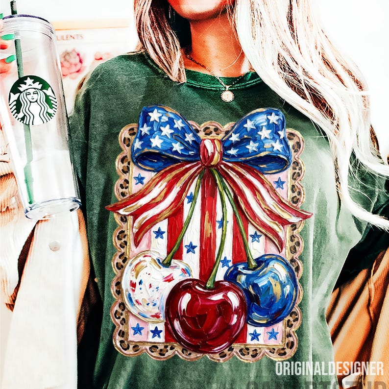 May include: Green t-shirt featuring a patriotic design with a blue bow adorned with white stars, red and white striped elements, and three cherries. The design is framed with a leopard print border. The text "ORIGINALDESIGNER" is visible at the bottom.
