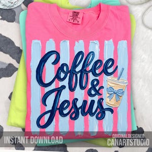 May include: A pink t-shirt with the words "Coffee & Jesus" in dark blue script, set against light blue vertical stripes. A coffee cup graphic with a blue bow is also featured. The shirt is part of a Comfort Colors collection.