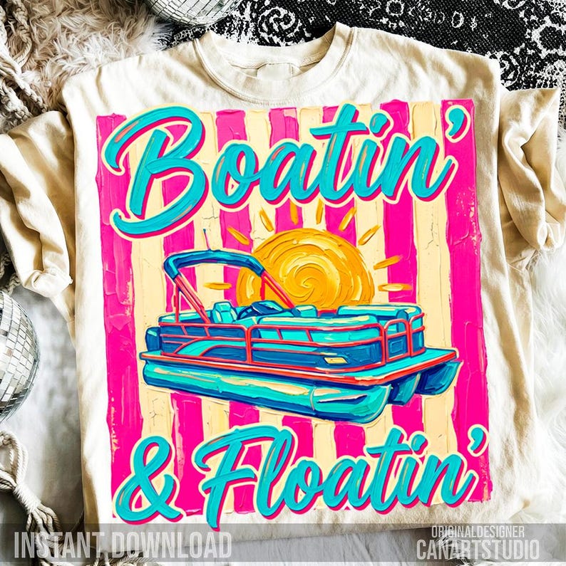 May include: Cream-colored t-shirt featuring a vibrant graphic with the words "Boatin' & Floatin'" in turquoise script. The design includes a turquoise and blue pontoon boat, a yellow sun, and pink and yellow vertical stripes.