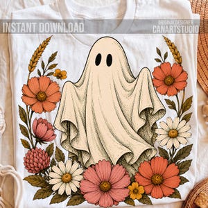 May include: A white t-shirt featuring a central graphic of a cream-colored ghost with black oval eyes, surrounded by a wreath of orange, pink, and white flowers with green leaves. The text INSTANT DOWNLOAD and CANARTSTUDIO is visible.