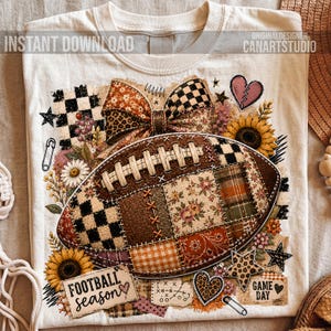 May include: A cream-colored t-shirt featuring a graphic of a football made of various fabric patterns including floral, plaid, and checkered prints. The design includes a large bow, sunflowers, stars, hearts, and the text "FOOTBALL season" and "GAME DAY".
