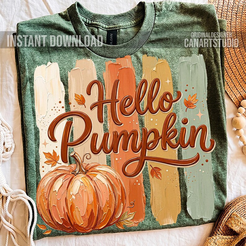 Puede incluir: Camiseta verde con un dise&ntilde;o de tem&aacute;tica oto&ntilde;al. El dise&ntilde;o presenta las palabras "Hello Pumpkin" en escritura marr&oacute;n, una ilustraci&oacute;n de calabaza y pinceladas coloridas. Las palabras "Instant Download" est&aacute;n en la esquina superior izquierda.