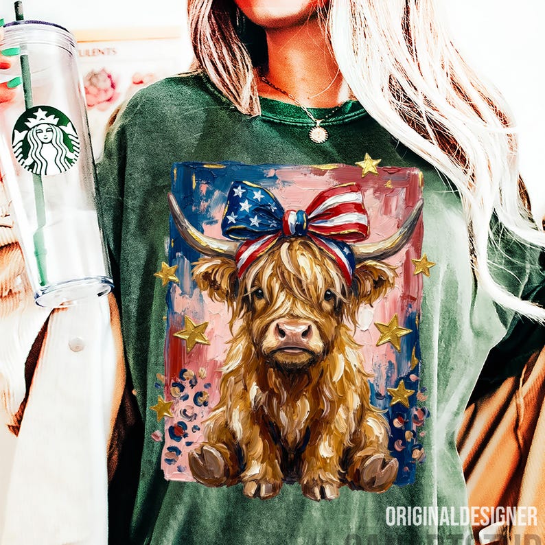 Peut inclure: T-shirt vert &agrave; manches longues avec une illustration de vache des Highlands orn&eacute;e d'un n&oelig;ud aux couleurs du drapeau am&eacute;ricain et d'&eacute;toiles dor&eacute;es. L'&oelig;uvre est plac&eacute;e sur un fond rouge, blanc et bleu. Le t-shirt porte le texte "ORIGINALDESIGNER".